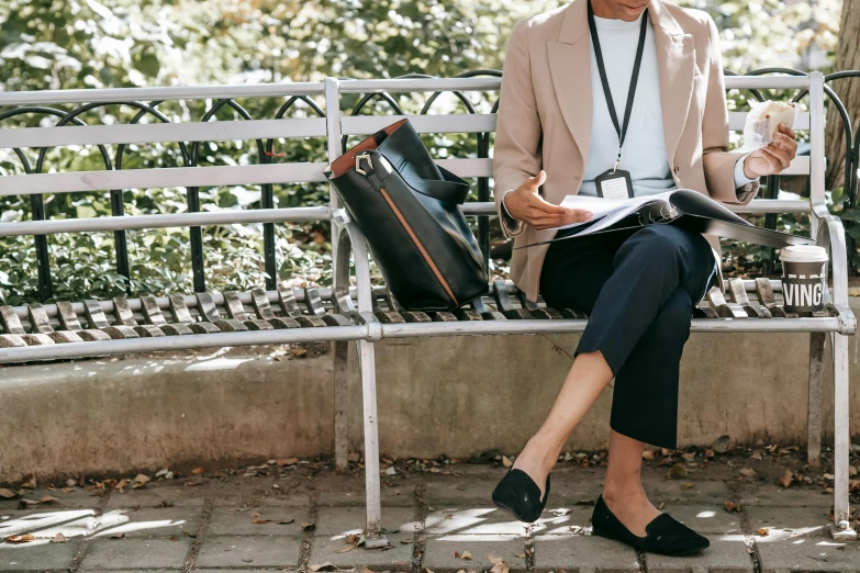 a woman sitting on a bench reading a book, by Nicolette Macnamara, trending on pexels, happening, he is carrying a black briefcase, black loafers, metallic neoprene woman, black and terracotta