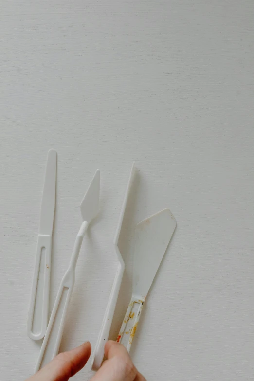 a close up of a person holding a knife and fork, by Jessie Algie, plasticien, white with gold accents, lined up horizontally, various sizes, glass