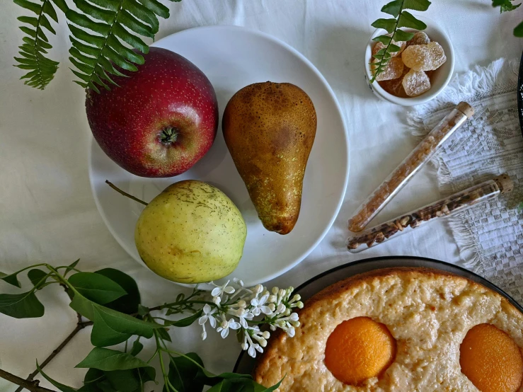 a pie sitting on top of a white plate next to a bowl of fruit, listing image, pears, ingredients on the table, botanicals