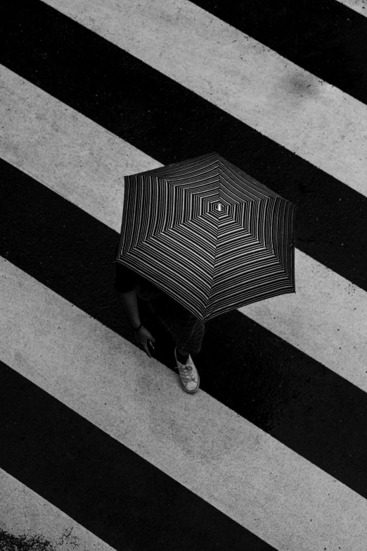 a black and white photo of a person holding an umbrella, a black and white photo, unsplash contest winner, square lines, top - down photograph, crosswalk, monochrome color
