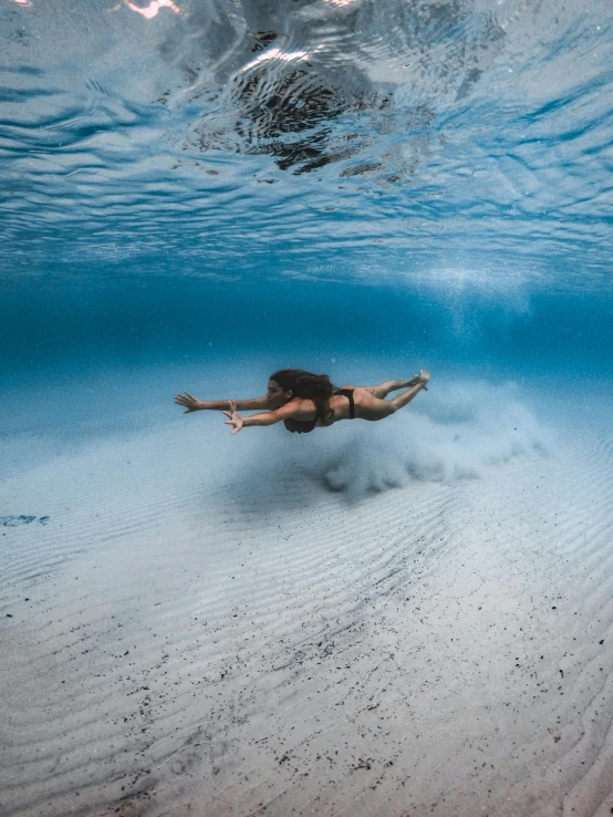 a woman in a bikini swims under the water, unsplash contest winner, intimidating floating sand, surfing, 500px photos, taken on go pro hero8