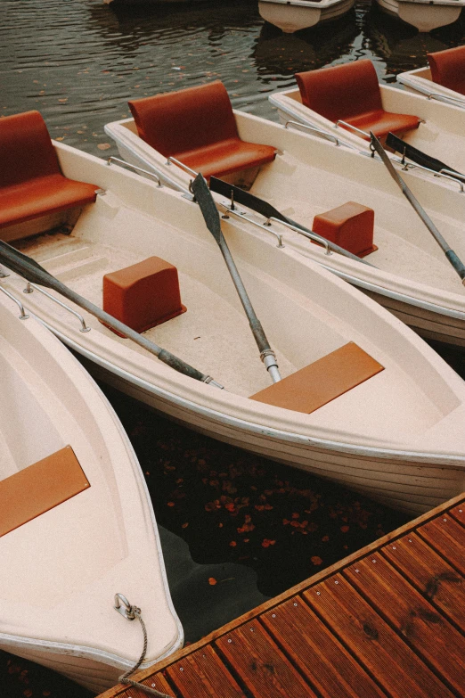 a group of boats sitting on top of a wooden dock, up-close, rowing boat, brown and cream color scheme, as photograph