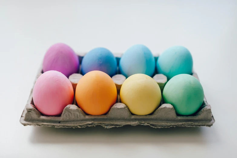 a carton of colored eggs sitting on top of a table, pastel faded grey rainbow, multiple stories, product shot, thumbnail