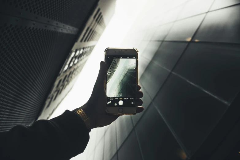 a person holding up a cell phone in front of a building, pexels contest winner, modernism, dark. no text, looking up at the camera, iphone video, high resolution