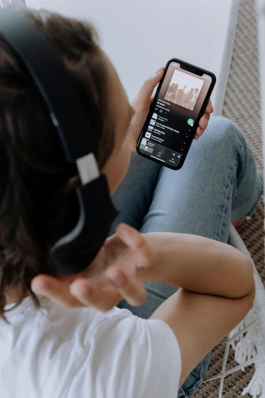 a woman sitting on a chair holding a cell phone, an album cover, trending on pexels, gaming headset, zoomed in, laying down, trending on spotify