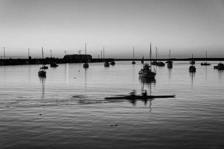 a group of boats floating on top of a body of water, a black and white photo, pexels contest winner, calm evening, sport, paddle of water, port