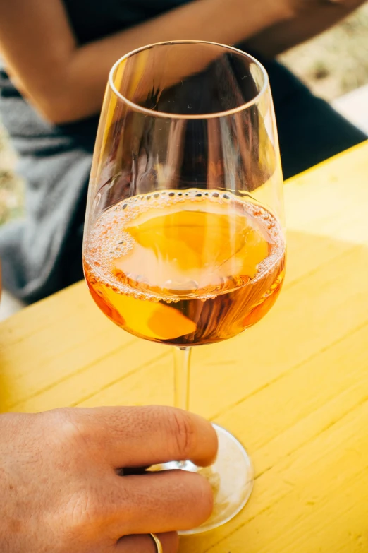 a person sitting at a table with a glass of wine, inspired by Jacopo Bellini, pexels contest winner, pink and yellow, loosely cropped, summer day, very grainy
