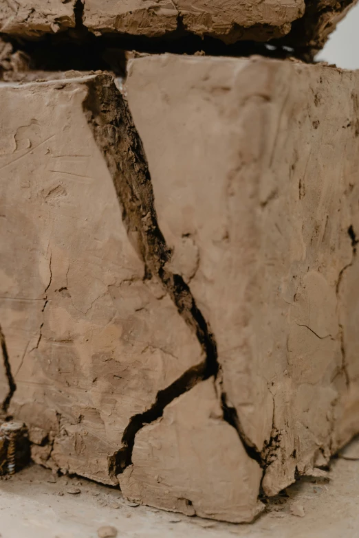 a piece of clay sitting on top of a pile of rocks, by Thomas de Keyser, trending on pexels, conceptual art, subsurface cracks, light - brown wall, wood texture, leonardo davinci detail