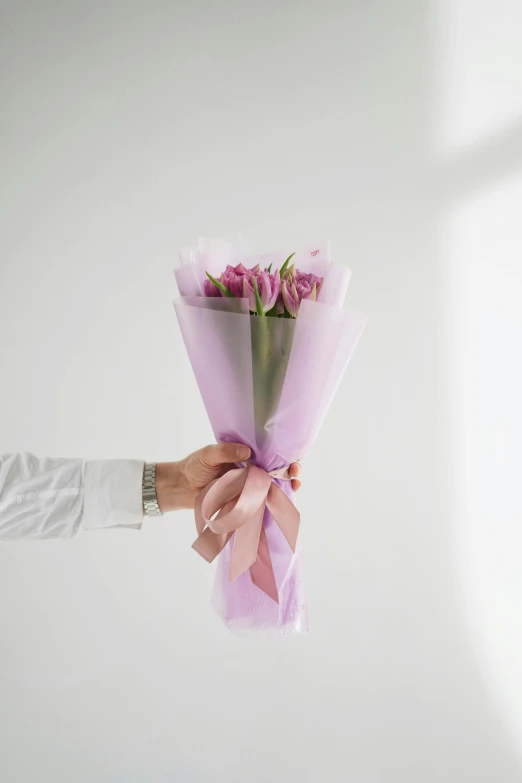 a person holding a bouquet of pink roses, slightly minimal, purple themed, wrapped, no text