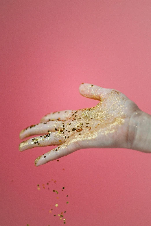 a woman's hand is sprinkled with gold glitter, by Julia Pishtar, renaissance, pigment, elliot alderson, extra crisp image