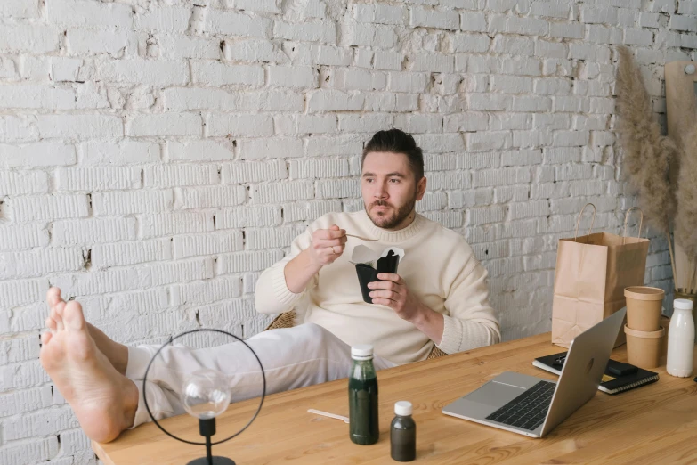 a man sitting at a table with a cell phone in his hand, with a white mug, full of things, abcdefghijklmnopqrstuvwxyz, thumbnail