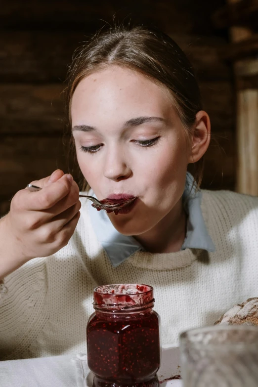 a woman sitting at a table with a spoon in her mouth, inspired by Louisa Matthíasdóttir, pexels contest winner, maple syrup & hot fudge, teenager girl, raspberry, closeup - view