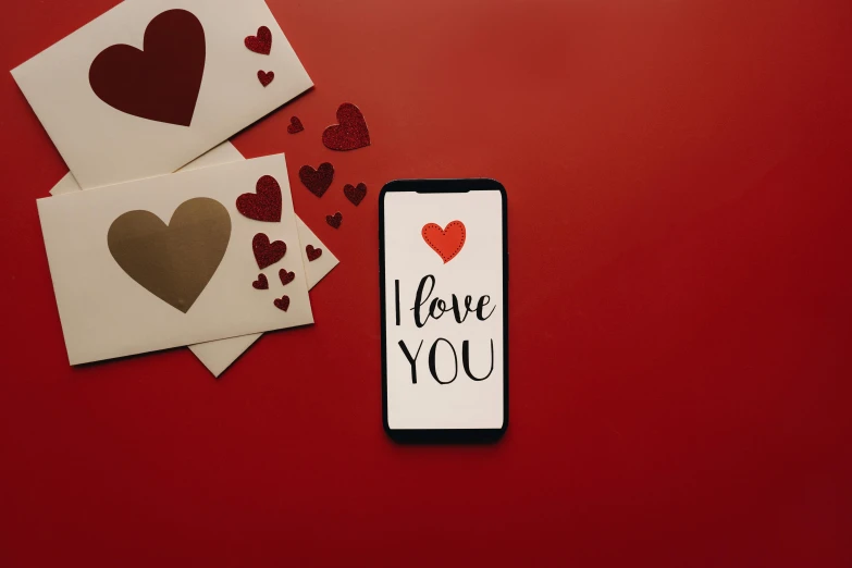 a cell phone sitting on top of a red table, by Julia Pishtar, trending on pexels, graffiti, i love you, several hearts, background image