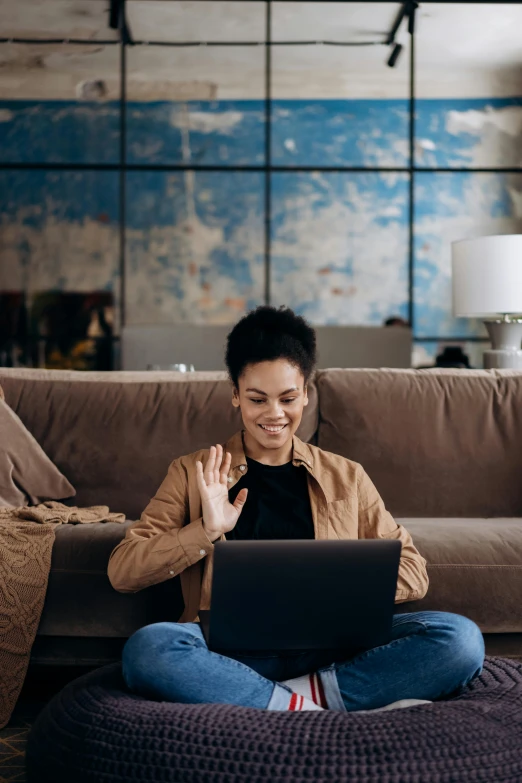 a woman sitting on a couch using a laptop, pexels contest winner, waving, mixed-race woman, official screenshot, brown