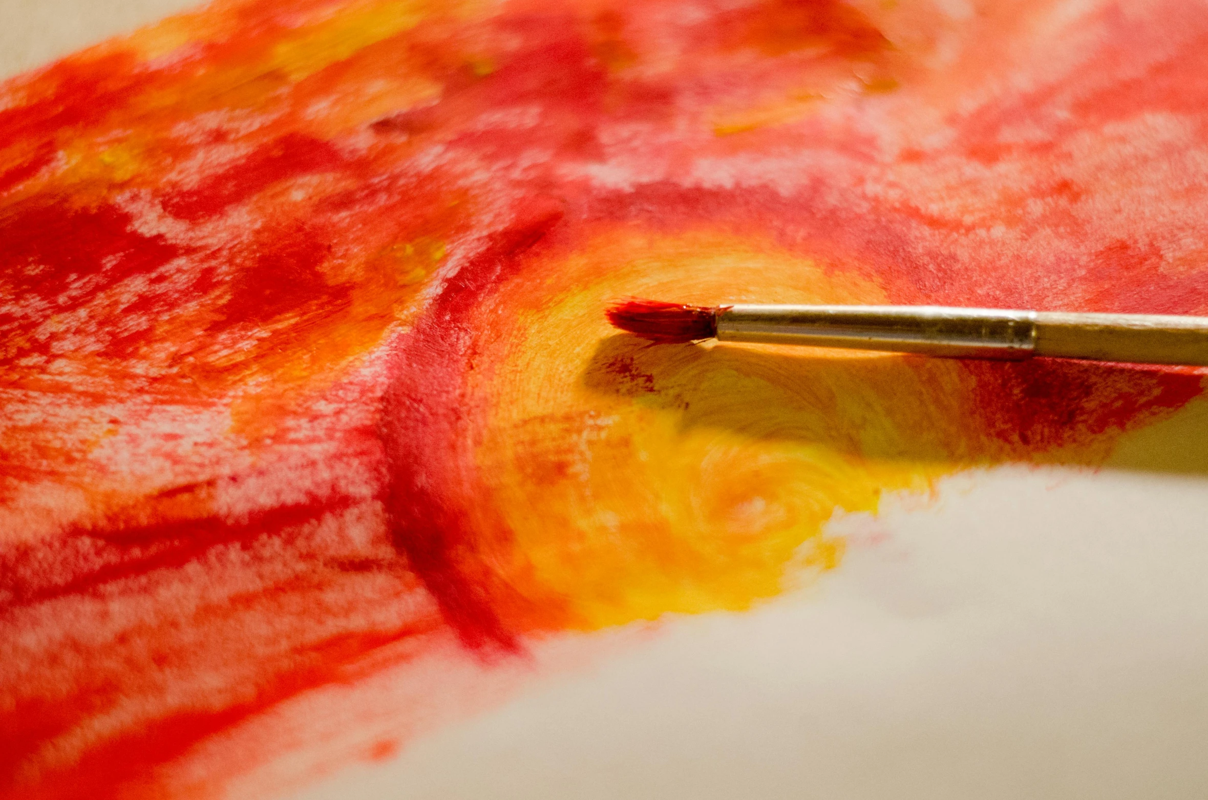 a close up of a paint brush on a piece of paper, a watercolor painting, inspired by Emil Nolde, pexels, yellow and red, painting on canvas, an artistic pose, light red and orange mood