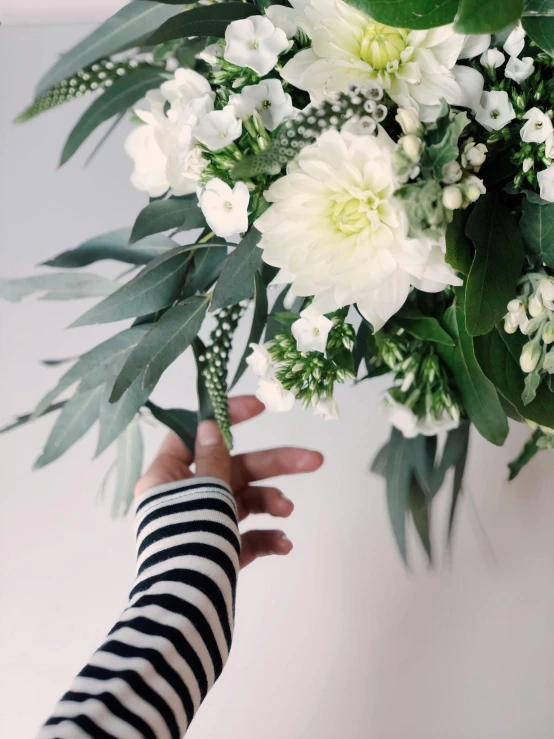 a person holding a bouquet of white flowers, inspired by François Boquet, black and white spots, eucalyptus, extra detail, pale greens and whites