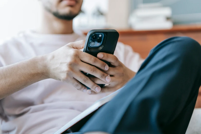 a man sitting on a couch holding a cell phone, trending on pexels, iphone 13, avatar image, bottom angle, someone sits in bed