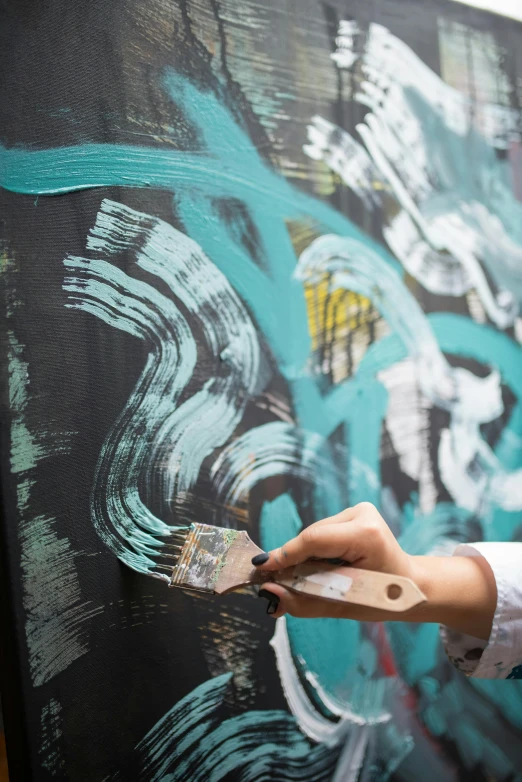 a woman painting on a wall with a brush, an acrylic painting, inspired by Hans Hartung, trending on unsplash, black and aqua colors, vibrant patterns, public art, on canvas