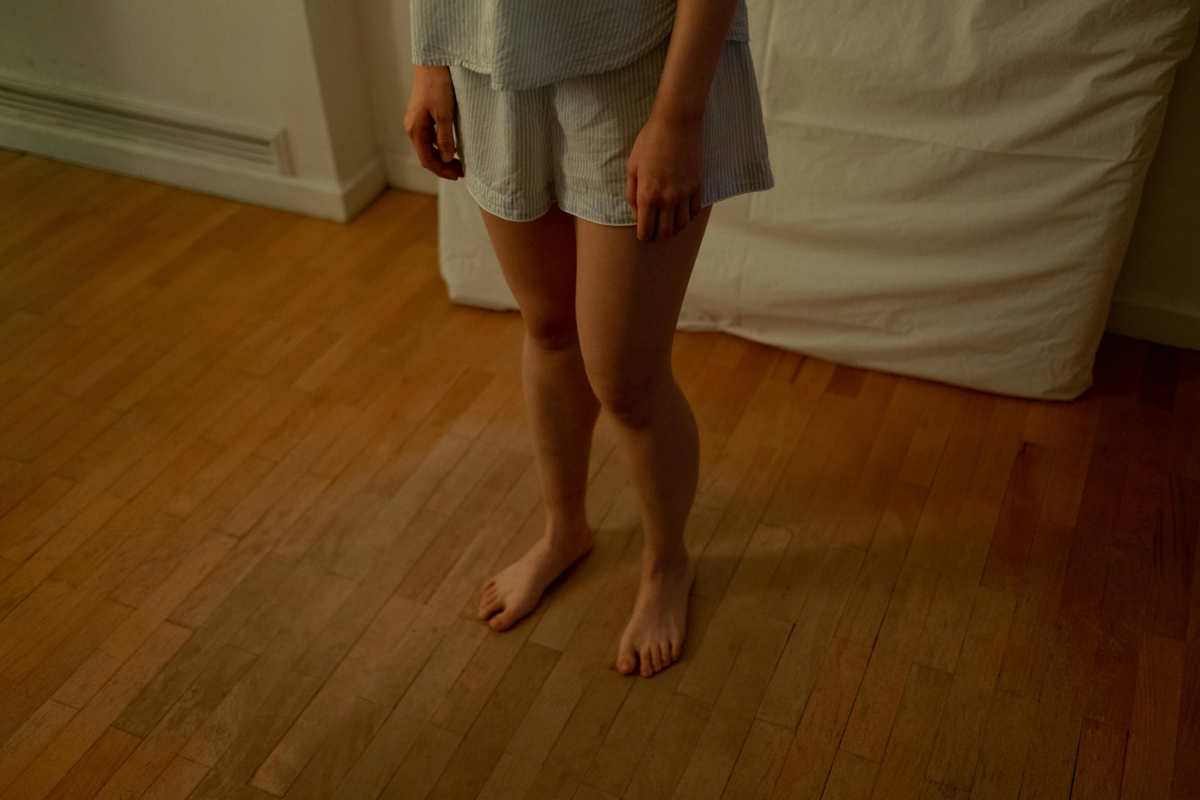 a woman standing on a hard wood floor, inspired by Elsa Bleda, unsplash, hyperrealism, shorts, nightgown, low quality photo, ignant