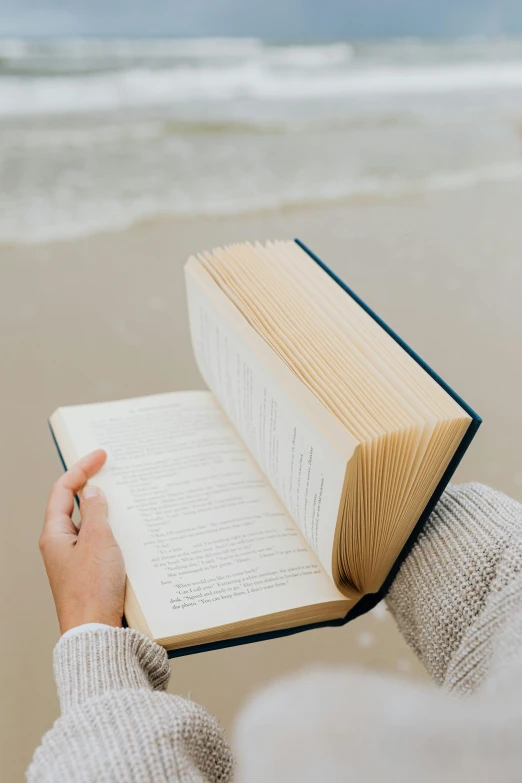 a woman reading a book on the beach, by Carey Morris, pexels contest winner, plain background, vertical orientation, moving poetry, curled up on a book