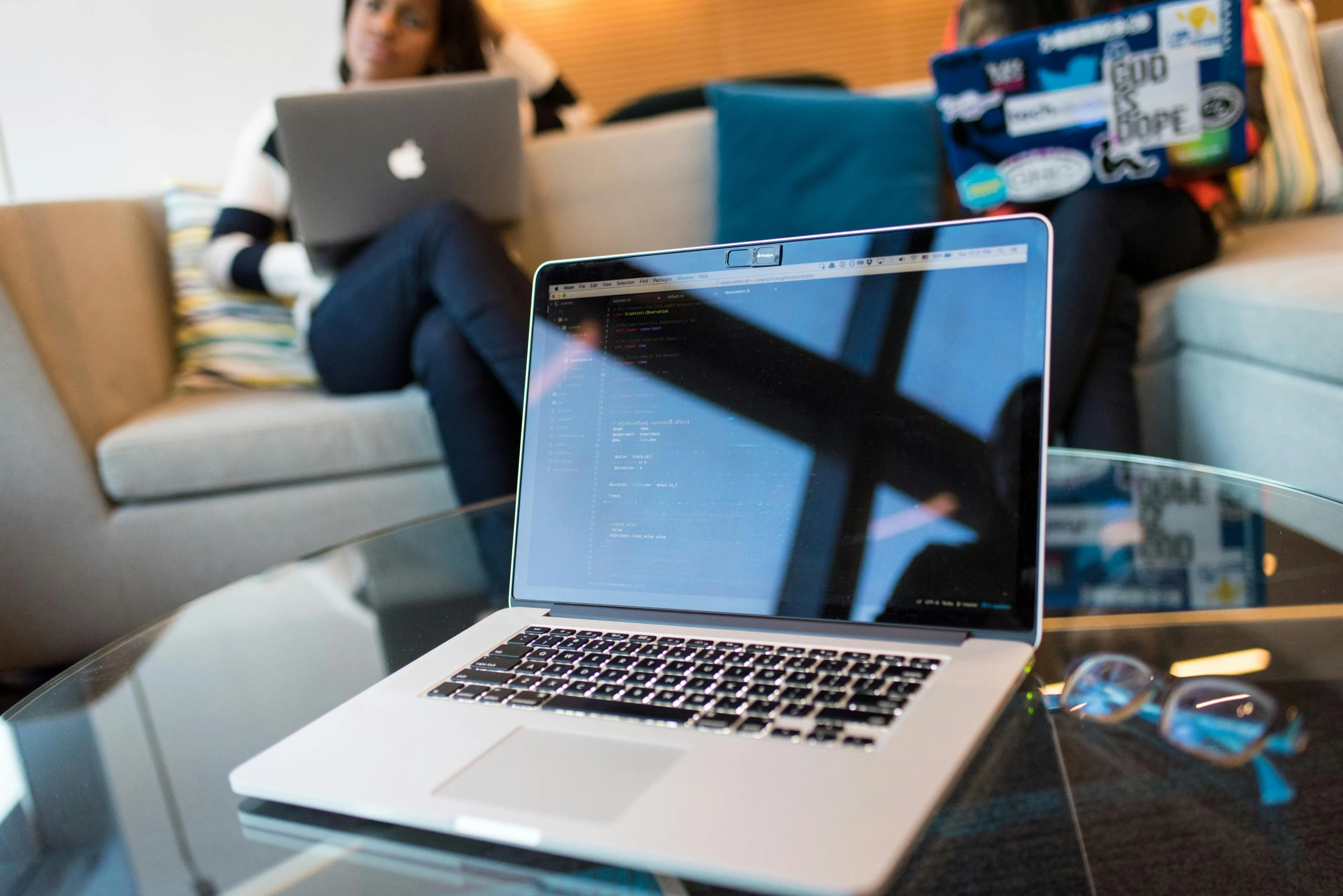 a laptop computer sitting on top of a glass table, by Carey Morris, pexels, figuration libre, coding, couch desk, person in foreground, with an intricate