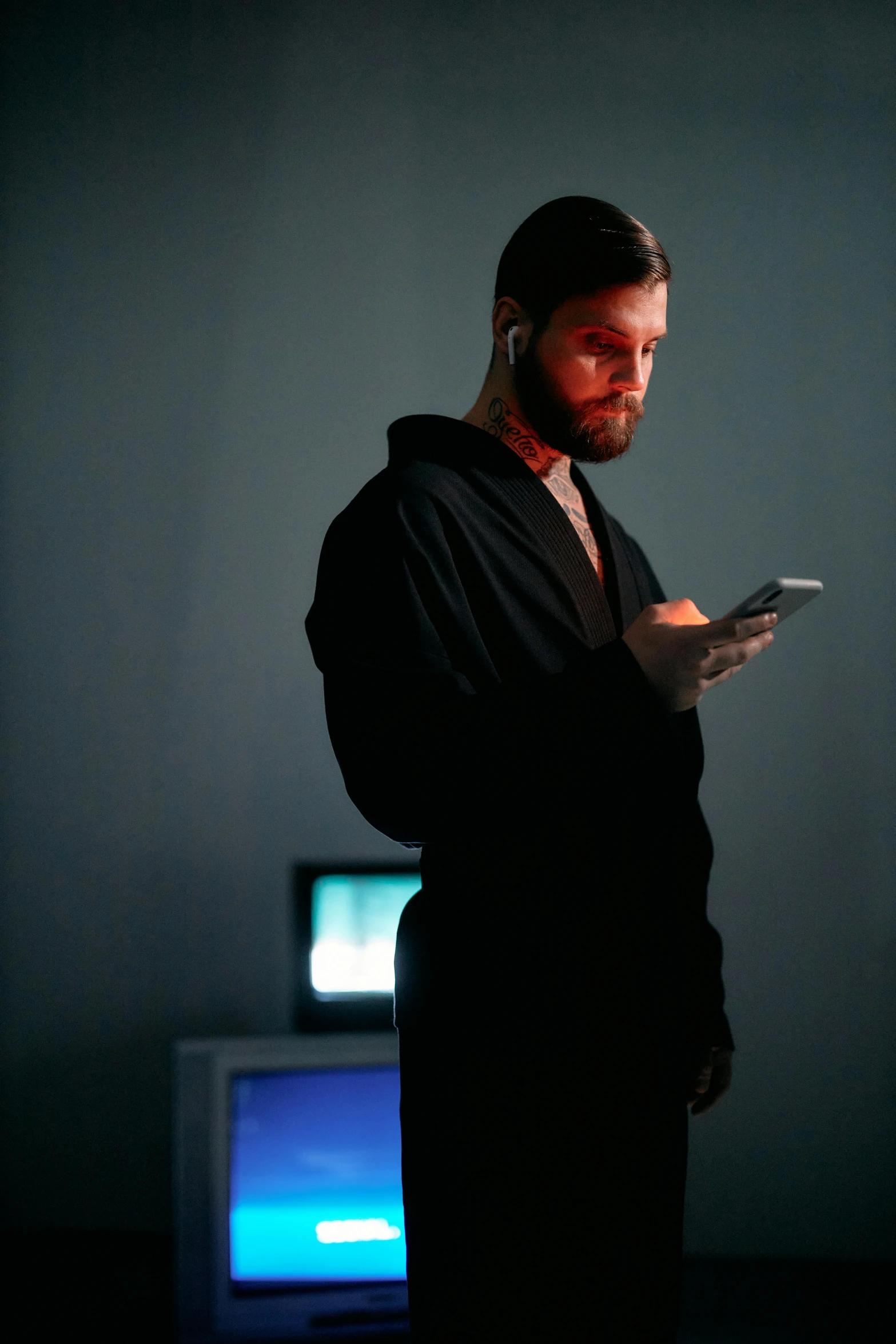a man standing in front of a television holding a cell phone, trending on reddit, renaissance, sith lord. dramatic lighting, very attractive man with beard, paranoid android, black reflect robe