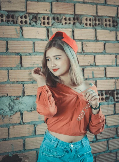 a woman standing in front of a brick wall, by Max Buri, unsplash, tachisme, wearing a cute top, red color theme, square, 18 years old