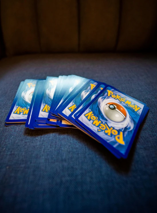 a pile of pokemon cards sitting on top of a couch, blue rays, - 9, loose, swoosh