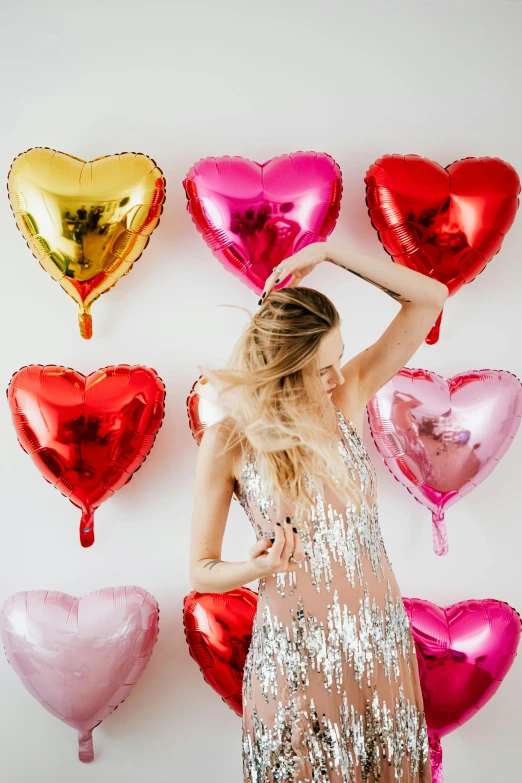 a woman standing in front of a wall of heart shaped balloons, a photo, by Julia Pishtar, trending on pexels, embellished sequined, product introduction photo, flowy, blonde