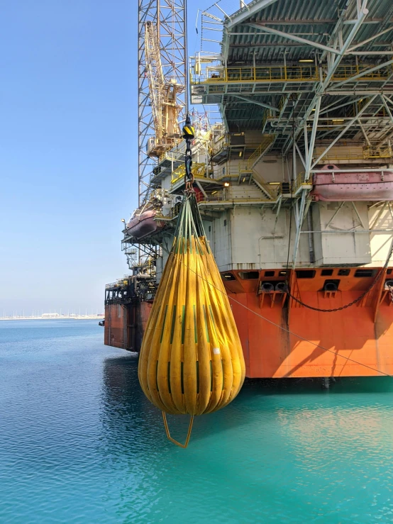 a large yellow buoy sitting on top of a body of water, carrying big sack, mechanical superstructure, award-winning shot, gulf