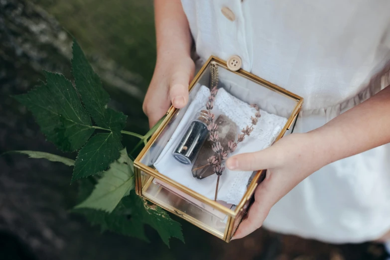 a close up of a person holding a box, a picture, inspired by Eden Box, stone and glass and gold, female explorer mini cute girl, potions, photo shoot