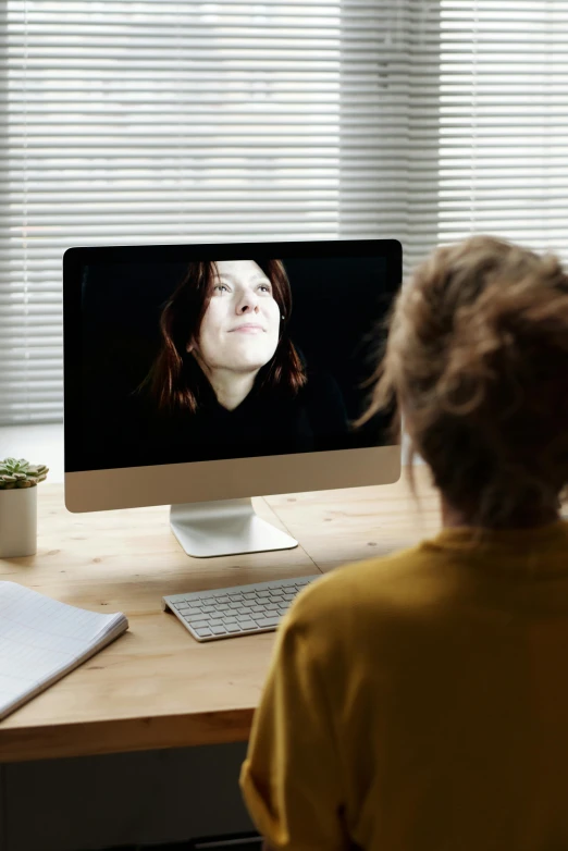 a woman sitting at a desk in front of a computer, inspired by Anna Füssli, trending on pexels, video art, emotional face shot, mobile learning app prototype, person in foreground, webcam