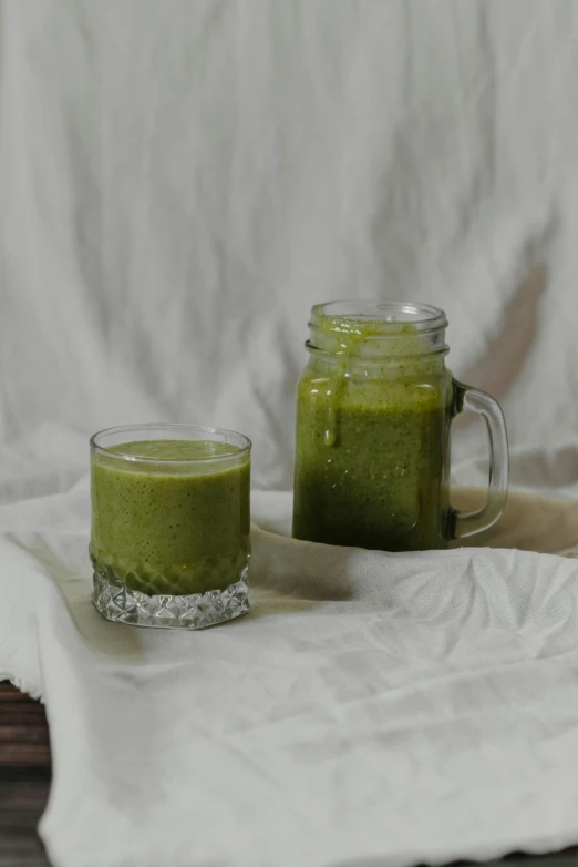 a glass of green smoothie next to a jar of green smoothie, a picture, unsplash, renaissance, sao paulo, made of glazed, show, malaysian