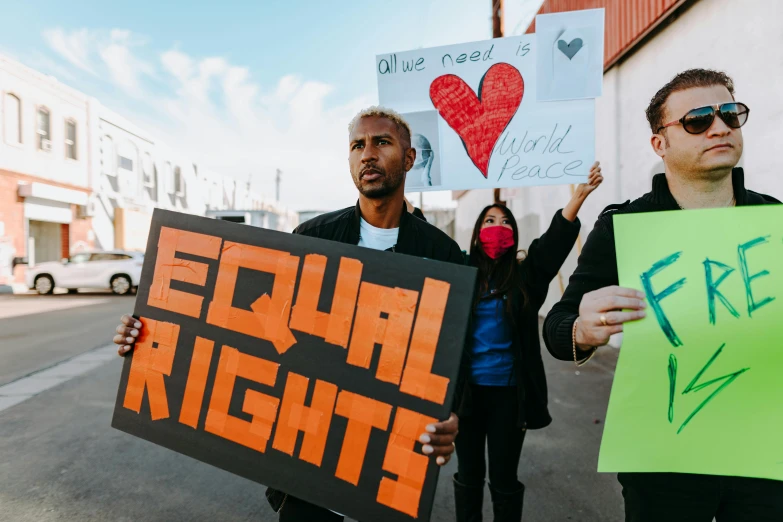 a group of people holding signs on a street, by Julia Pishtar, trending on pexels, gay rights, 3 - piece, the right from wrong, aida muluneh