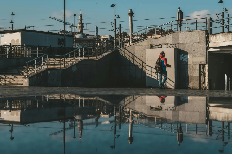 a man standing next to a puddle of water, unsplash contest winner, hyperrealism, architecture photo, surrounding the city, mirroring, at a skate park