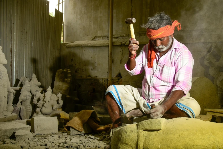 a man that is sitting down with a hammer, pexels contest winner, bengal school of art, made from old stone, thumbnail, small manufacture, avatar image