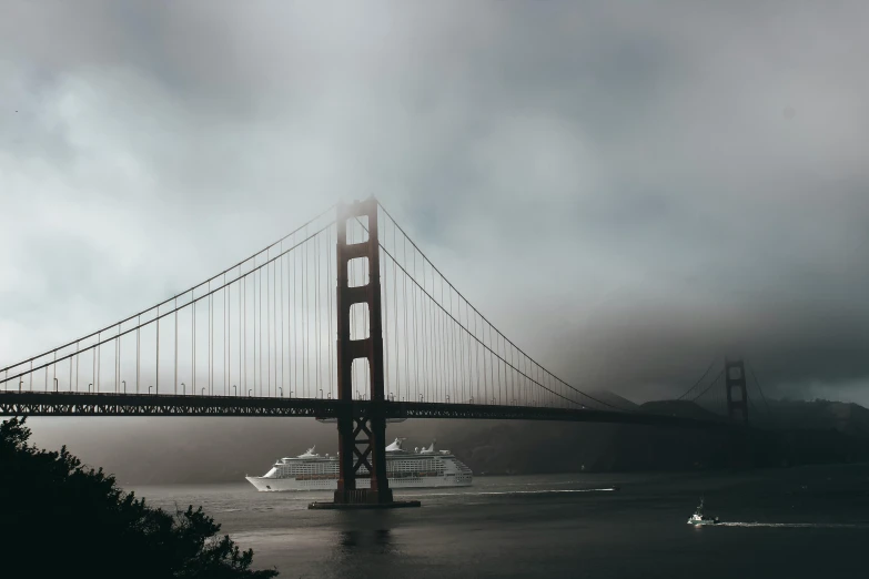 a bridge over a body of water under a cloudy sky, pexels contest winner, modernism, moist foggy, ships with sails underneath, california;, light grey mist