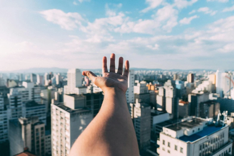 a person standing on top of a tall building, pexels contest winner, five fingers on the hand, floating over a city sidewalk, são paulo, scaled arm