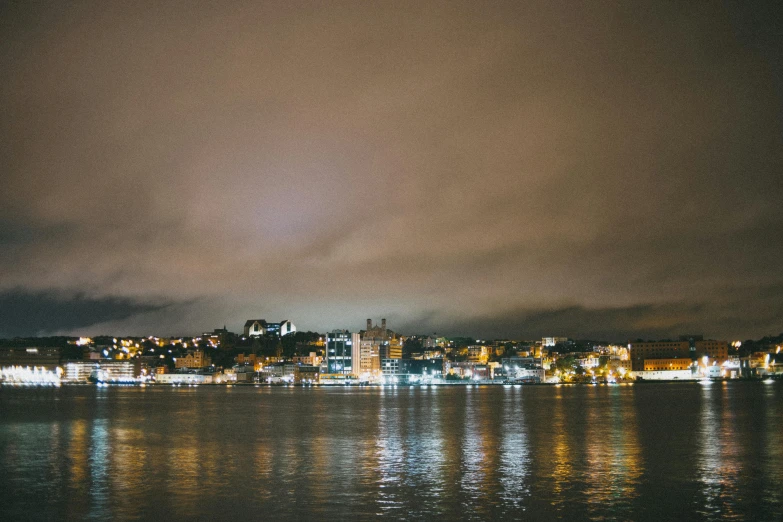 a large body of water next to a city at night, pexels contest winner, on a cloudy day, manly, brown, a cozy