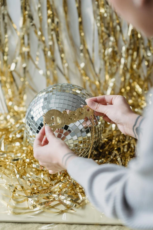 a close up of a person holding a disco ball, gold decorations, vinyl material, profile image