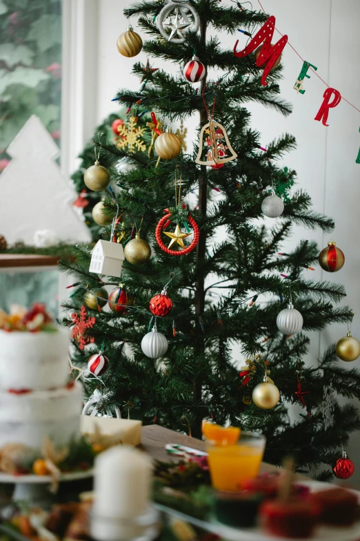 a table topped with plates of food next to a christmas tree, by Julia Pishtar, ornament, premium quality, multiple stories, close up details