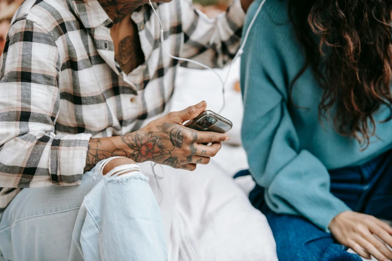 a man sitting on top of a bed next to a woman, a tattoo, trending on pexels, cell phone, earbuds, animated, 1 2 9 7