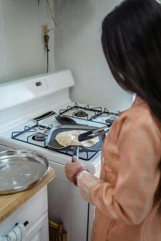 a woman standing in a kitchen next to a stove, by Arabella Rankin, unsplash, flat pancake head, plating, arabian, mid action