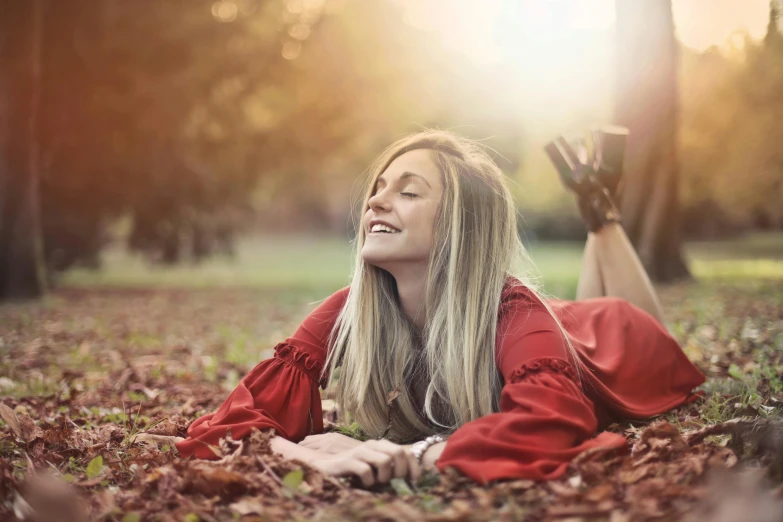 a woman laying on the ground in the leaves, pexels contest winner, smiling :: attractive, wearing red clothes, soft golden light, 15081959 21121991 01012000 4k