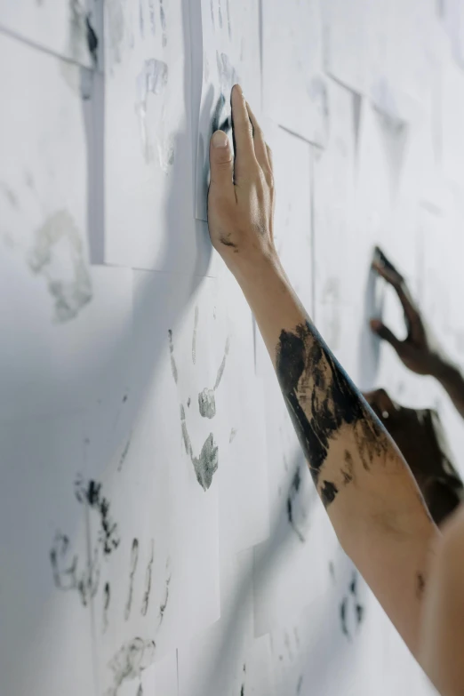 a person that is writing on a wall, a charcoal drawing, inspired by Antoni Tàpies, trending on pexels, hands in air, showstudio, leaning towards watercolor, tattoos all over the skin