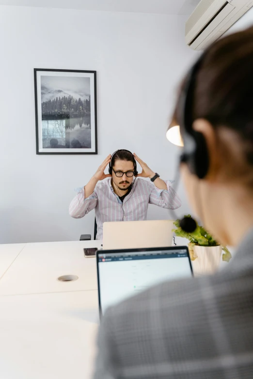 a man sitting at a table with a laptop in front of him, trending on pexels, in an call centre office, headphones on his head, a python programmer's despair, in a meeting room