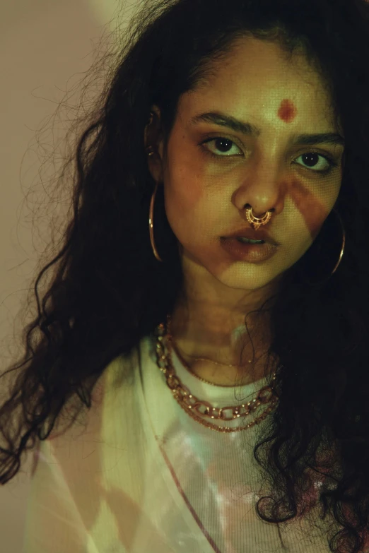 a woman with makeup and piercings on her face, an album cover, inspired by Elsa Bleda, trending on pexels, renaissance, hinduism, young himalayan woman, cynthwave, 33mm photo