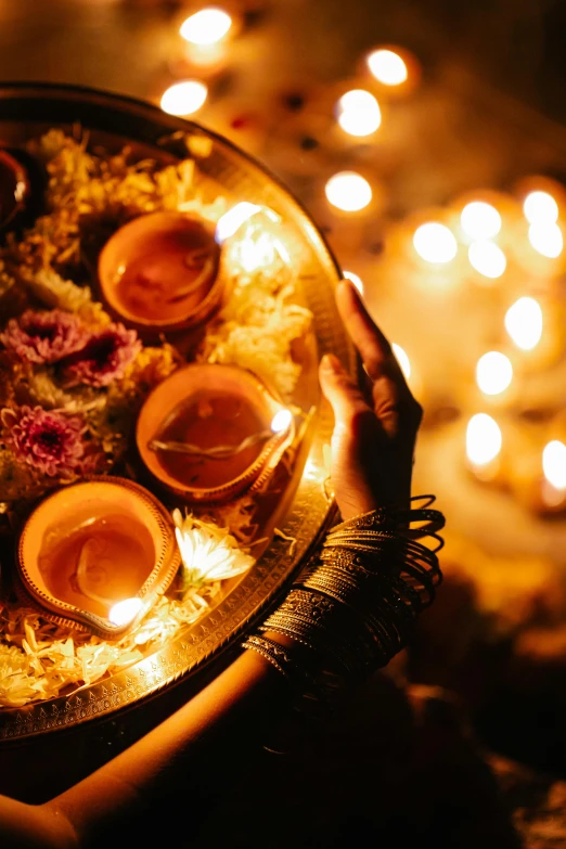 a person holding a tray with lit candles, hindu ornaments, bursting with holy light, trending, uplit