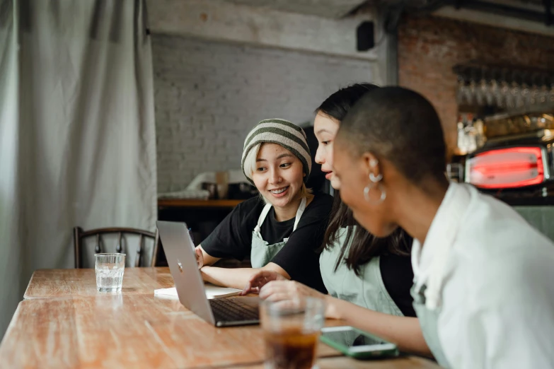a couple of women sitting at a table with a laptop, trending on pexels, aussie baristas, avatar image, malaysian, three women