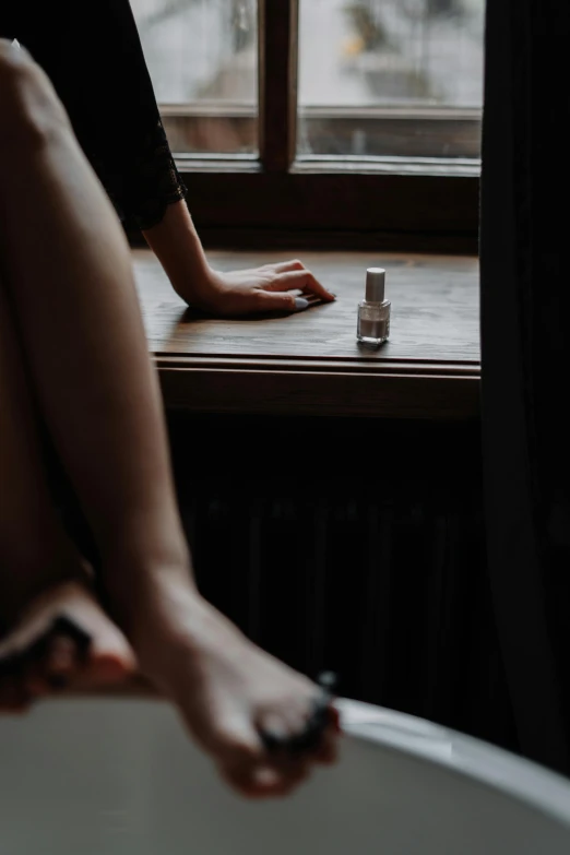 a woman sitting in a bath tub next to a window, inspired by Nan Goldin, trending on unsplash, nail polish, sitting on a mocha-colored table, 33mm photo, floating in perfume